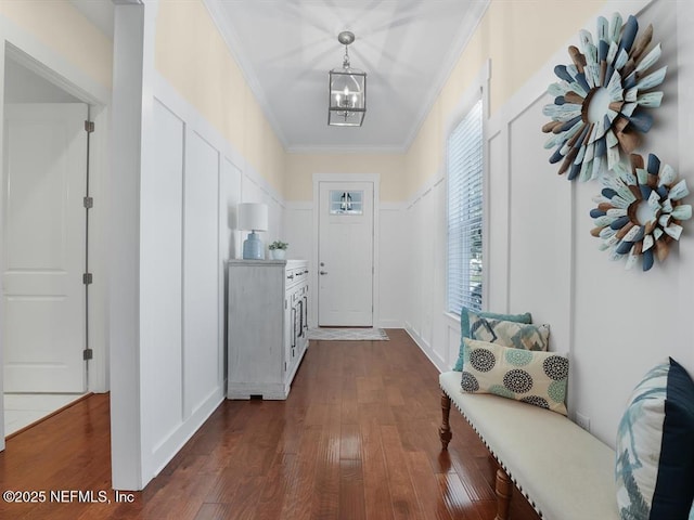 corridor with dark hardwood / wood-style floors, crown molding, and an inviting chandelier