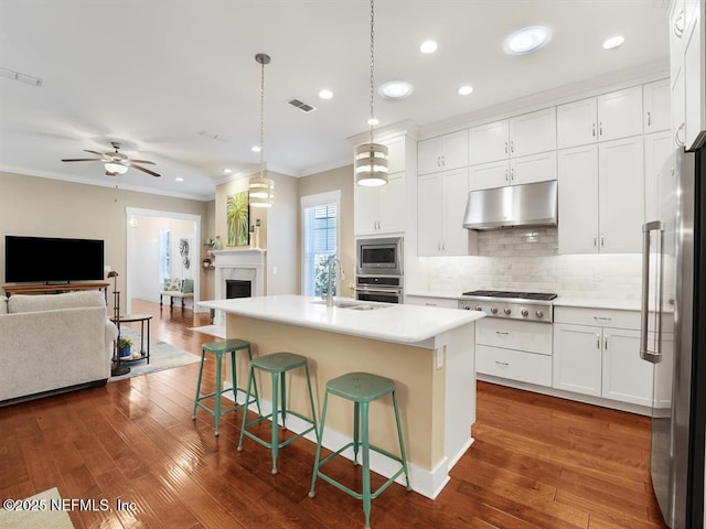 kitchen with sink, stainless steel appliances, an island with sink, pendant lighting, and white cabinets