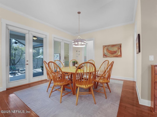 dining space with dark wood-type flooring, a notable chandelier, and ornamental molding