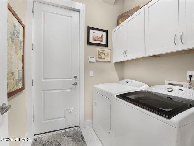 laundry area with washing machine and dryer, light tile patterned floors, and cabinets