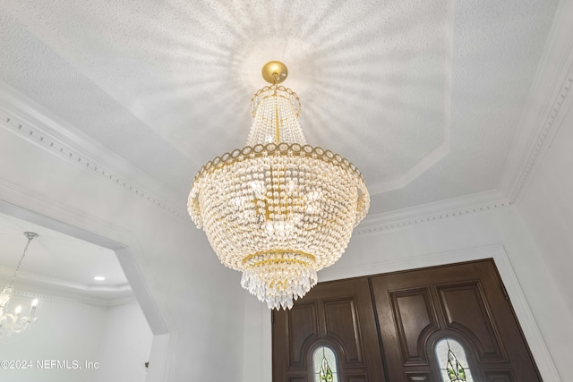 interior details with a raised ceiling, an inviting chandelier, and crown molding