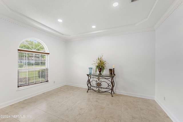 tiled empty room with a raised ceiling and crown molding