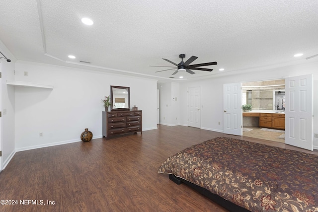 unfurnished bedroom featuring connected bathroom, ceiling fan, dark wood-type flooring, and a textured ceiling