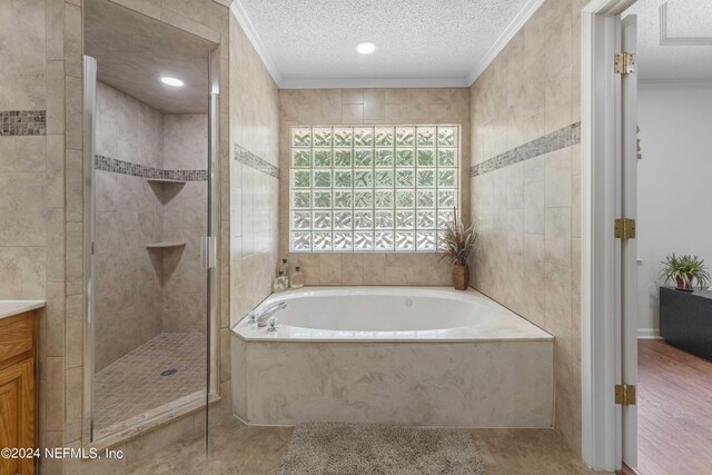 bathroom featuring a textured ceiling, vanity, crown molding, tile walls, and independent shower and bath