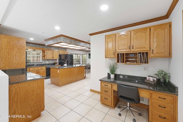 kitchen with sink, a center island, black appliances, built in desk, and ornamental molding