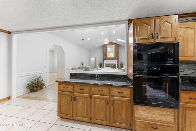 kitchen with black appliances, light tile patterned flooring, a textured ceiling, and dark stone counters