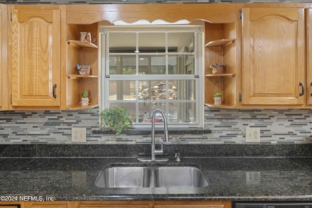 kitchen featuring dishwasher, sink, dark stone counters, and tasteful backsplash