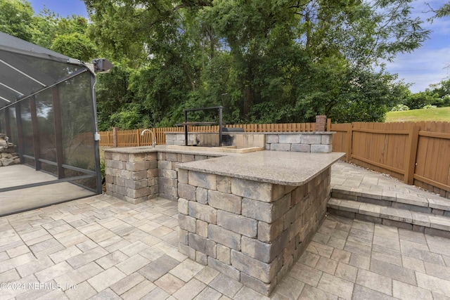 view of patio / terrace featuring glass enclosure and a bar