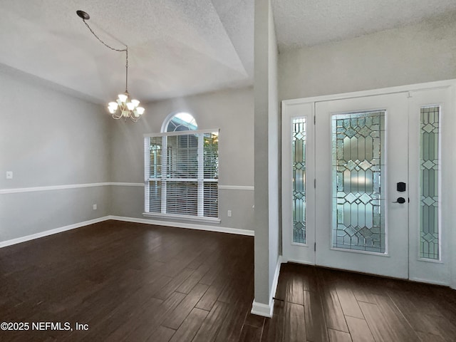 entryway with vaulted ceiling, dark hardwood / wood-style floors, a textured ceiling, and a notable chandelier