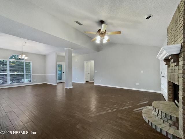 unfurnished living room with dark hardwood / wood-style flooring, vaulted ceiling, a textured ceiling, a fireplace, and ceiling fan with notable chandelier