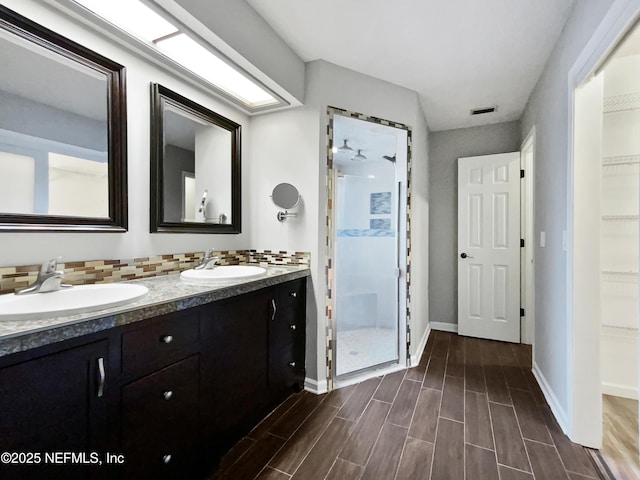 bathroom with vanity, tiled shower, and tasteful backsplash