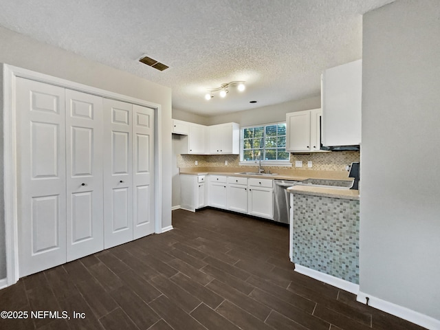 kitchen featuring backsplash, sink, white cabinets, and stainless steel dishwasher