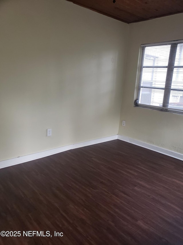 spare room with dark hardwood / wood-style flooring and wood ceiling