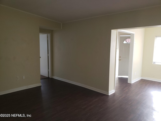 empty room featuring ornamental molding and dark wood-type flooring