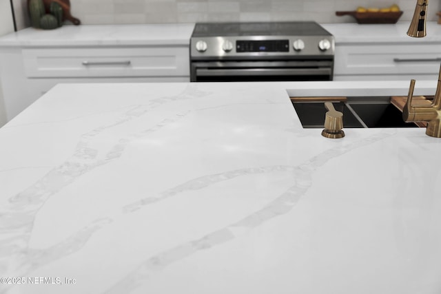 details featuring white cabinets, light stone countertops, and stainless steel electric range oven