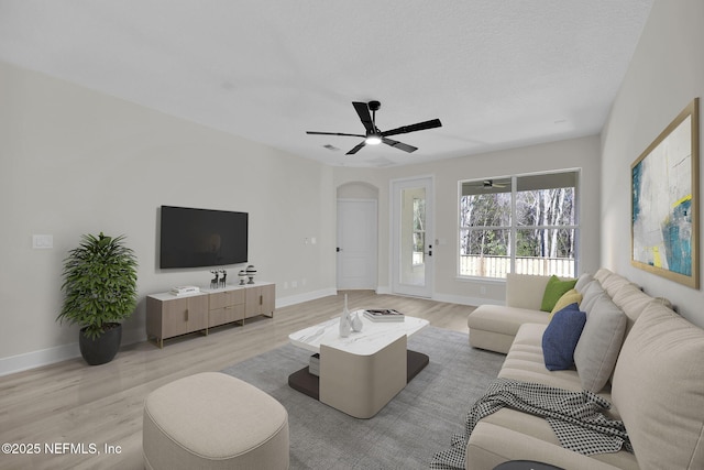 living room featuring ceiling fan, a textured ceiling, and light hardwood / wood-style flooring