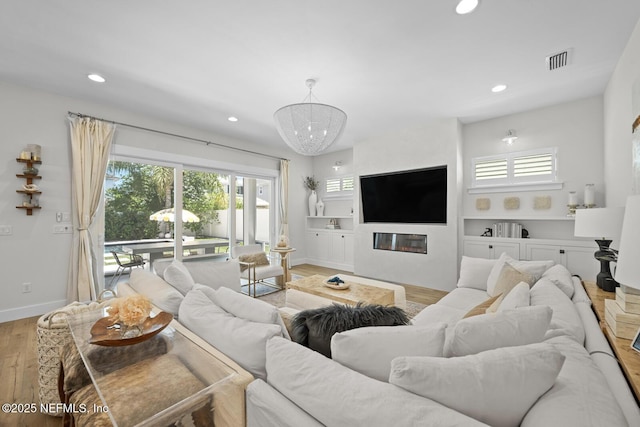 living room with built in features, light hardwood / wood-style flooring, and a notable chandelier