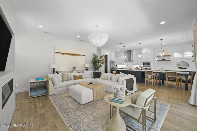 living room with an inviting chandelier and light wood-type flooring