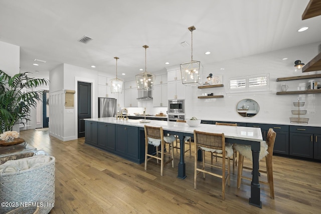 kitchen featuring a large island, stainless steel appliances, and decorative light fixtures