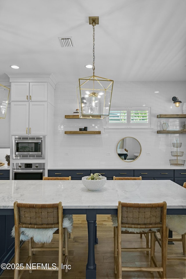 kitchen featuring a breakfast bar area, light stone countertops, white cabinetry, and stainless steel appliances