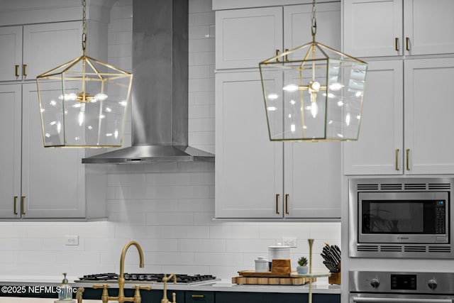 kitchen featuring decorative backsplash, decorative light fixtures, stainless steel appliances, and wall chimney range hood