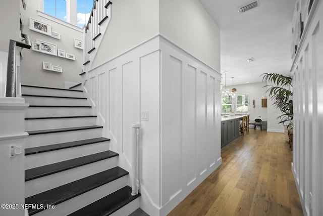 stairs featuring wood-type flooring and a notable chandelier