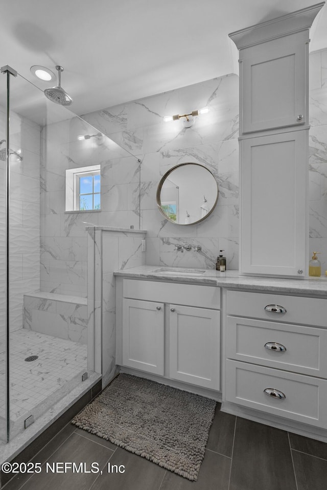 bathroom with vanity, a tile shower, and tile walls