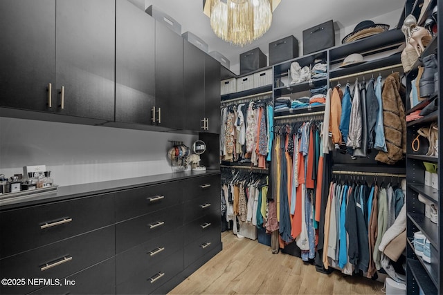 spacious closet with a chandelier and light hardwood / wood-style floors