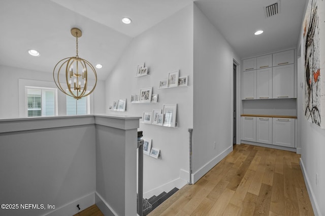 bar featuring white cabinets, decorative light fixtures, light hardwood / wood-style floors, and an inviting chandelier