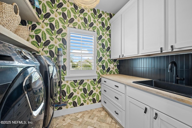 washroom with washing machine and clothes dryer, sink, and cabinets