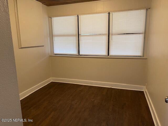 spare room featuring dark hardwood / wood-style flooring and wood ceiling