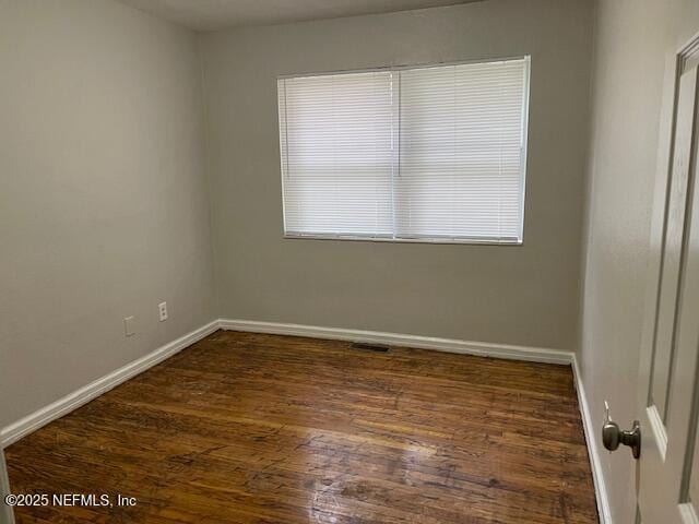 empty room featuring plenty of natural light and dark wood-type flooring