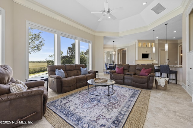 living room with sink, a raised ceiling, lofted ceiling, ceiling fan with notable chandelier, and ornamental molding