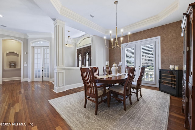 dining space featuring dark hardwood / wood-style floors, ornamental molding, a tray ceiling, and french doors