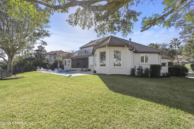 back of property with a lawn, a patio, and a fenced in pool