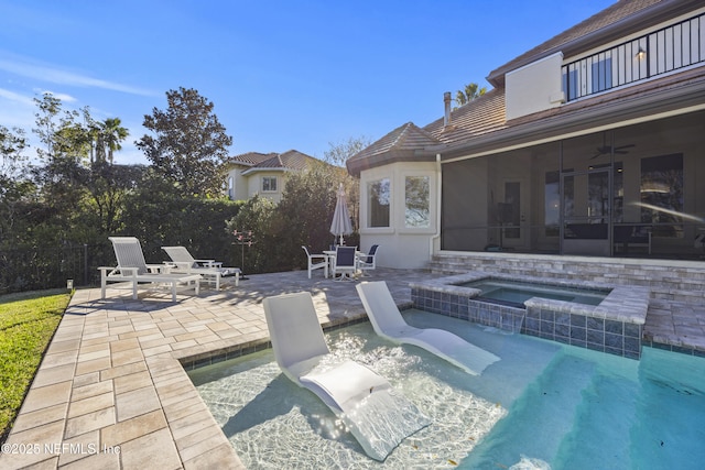 view of patio / terrace featuring a sunroom, a balcony, ceiling fan, and a pool with hot tub