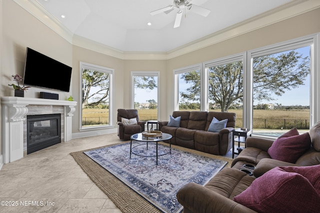 living room with a premium fireplace, ceiling fan, and ornamental molding