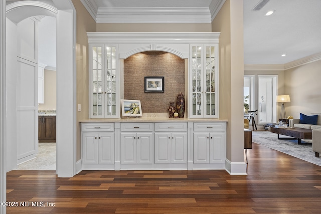 bar with white cabinets, ornamental molding, and dark wood-type flooring