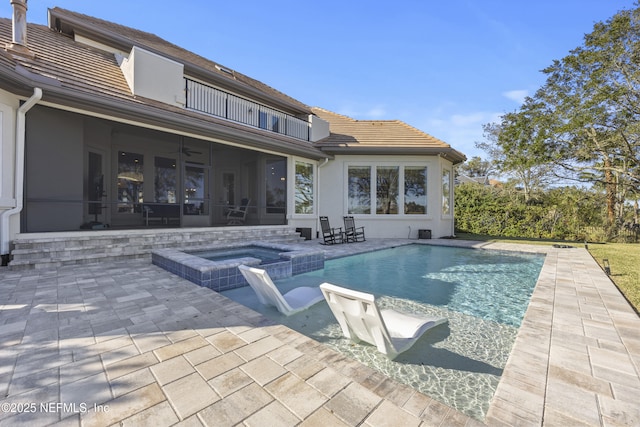 view of pool featuring a sunroom, an in ground hot tub, ceiling fan, and a patio