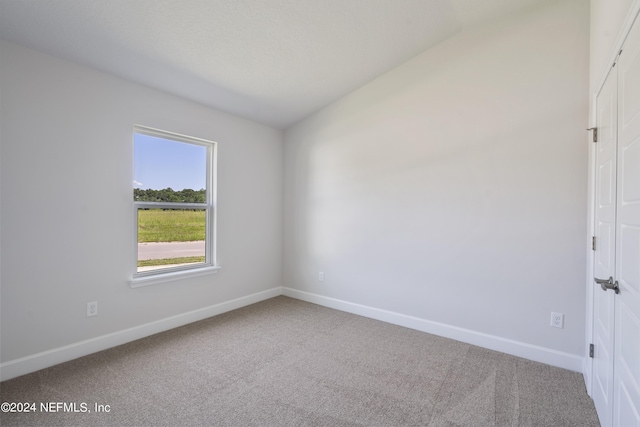 carpeted empty room with lofted ceiling