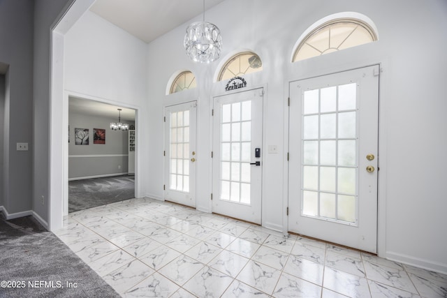 entrance foyer with a chandelier, light carpet, a towering ceiling, and a healthy amount of sunlight