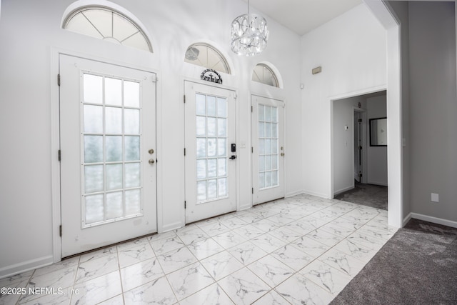 doorway featuring plenty of natural light, a towering ceiling, and a notable chandelier