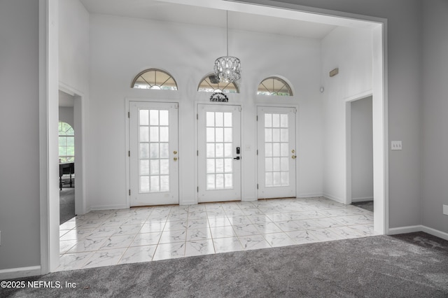 entryway with light carpet, a high ceiling, and a notable chandelier