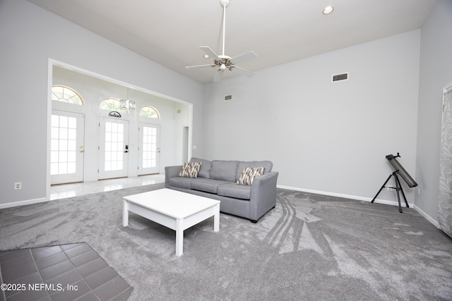 unfurnished living room with ceiling fan, a towering ceiling, and carpet floors