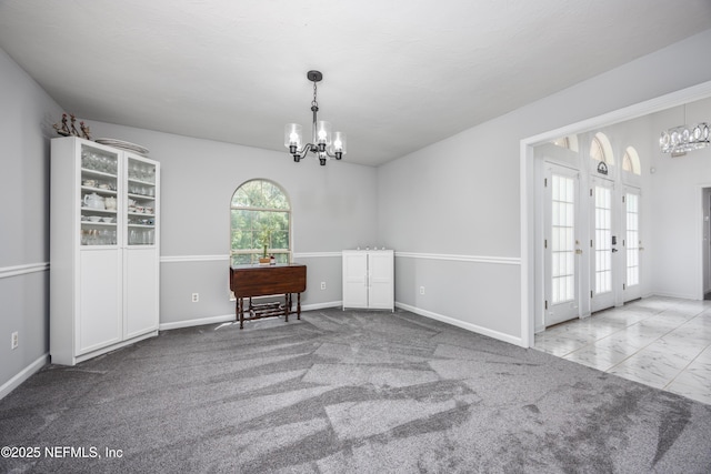 unfurnished room with a chandelier, french doors, and carpet floors