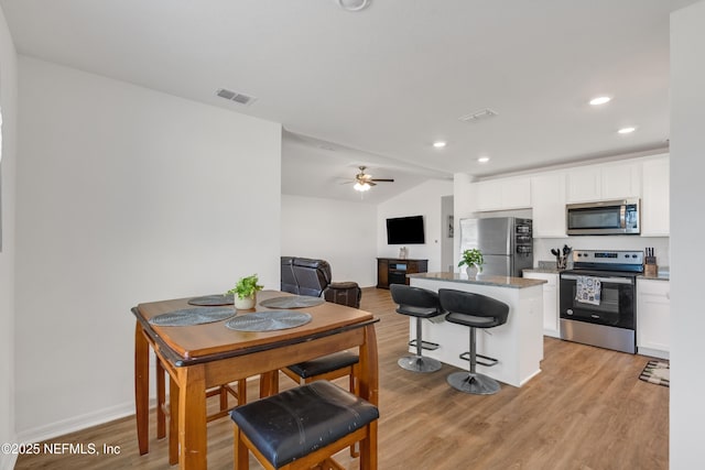 kitchen featuring stainless steel appliances, a kitchen island, a breakfast bar area, and white cabinets