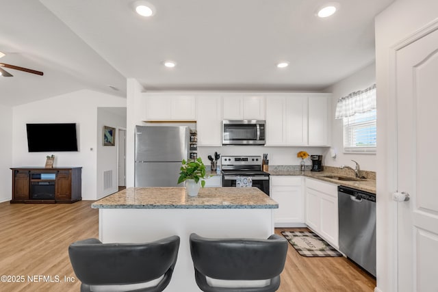 kitchen featuring a kitchen island, appliances with stainless steel finishes, white cabinets, and light stone counters