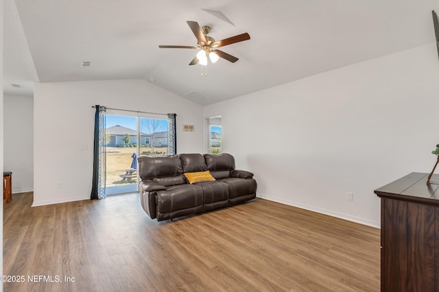 living room with ceiling fan, vaulted ceiling, and light wood-type flooring