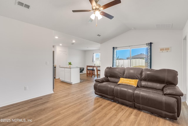 living room with ceiling fan, lofted ceiling, and light wood-type flooring