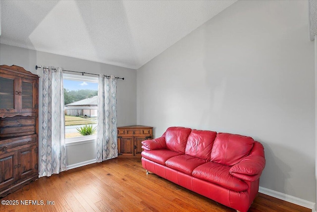 living room with a textured ceiling, hardwood / wood-style floors, and vaulted ceiling